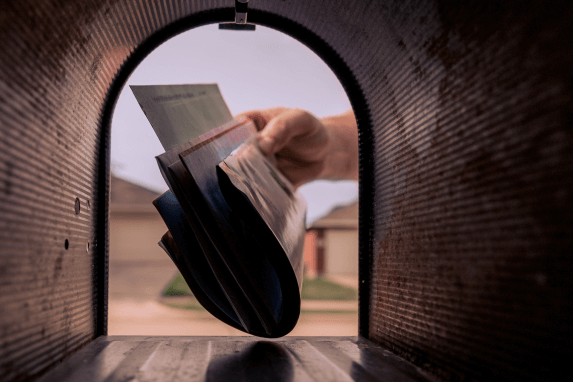 A stack of mail being delivered into a mailbox